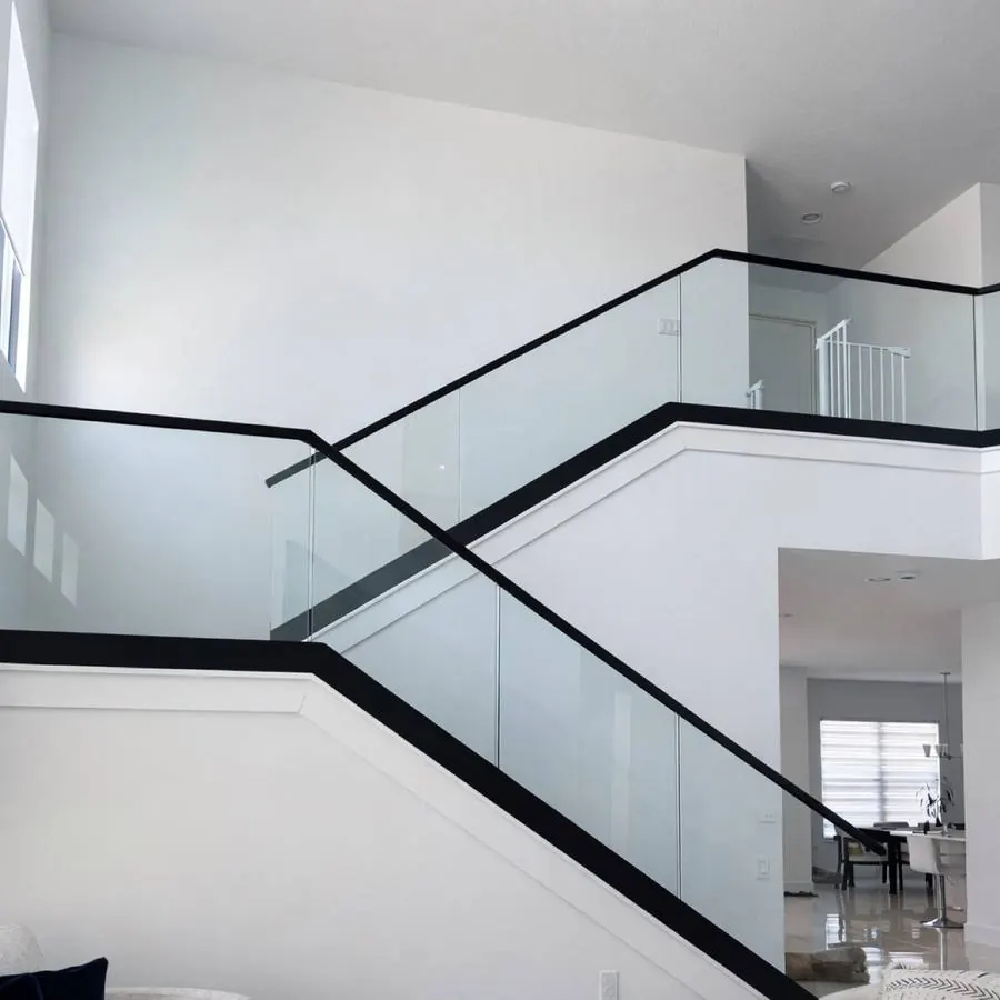 Interior glass stair railing with black handrail
